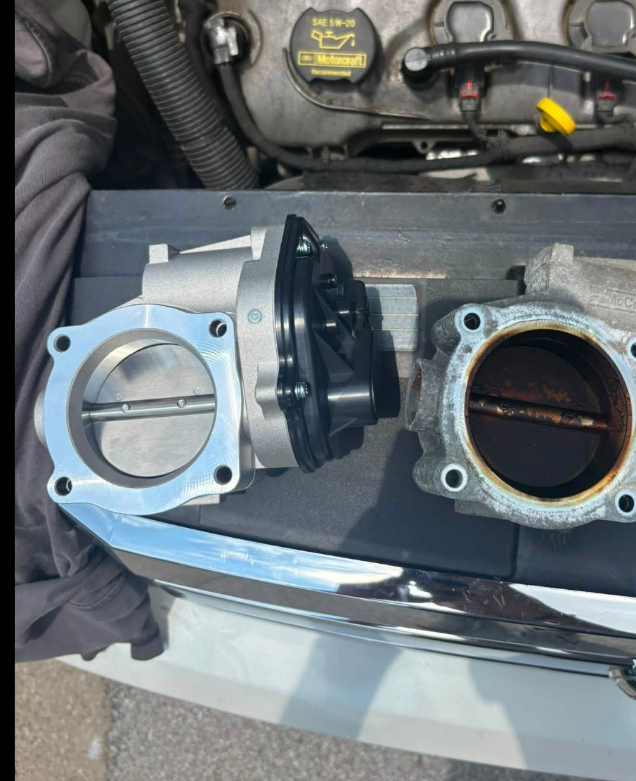 Old worn throttle body next to a new replacement throttle body
